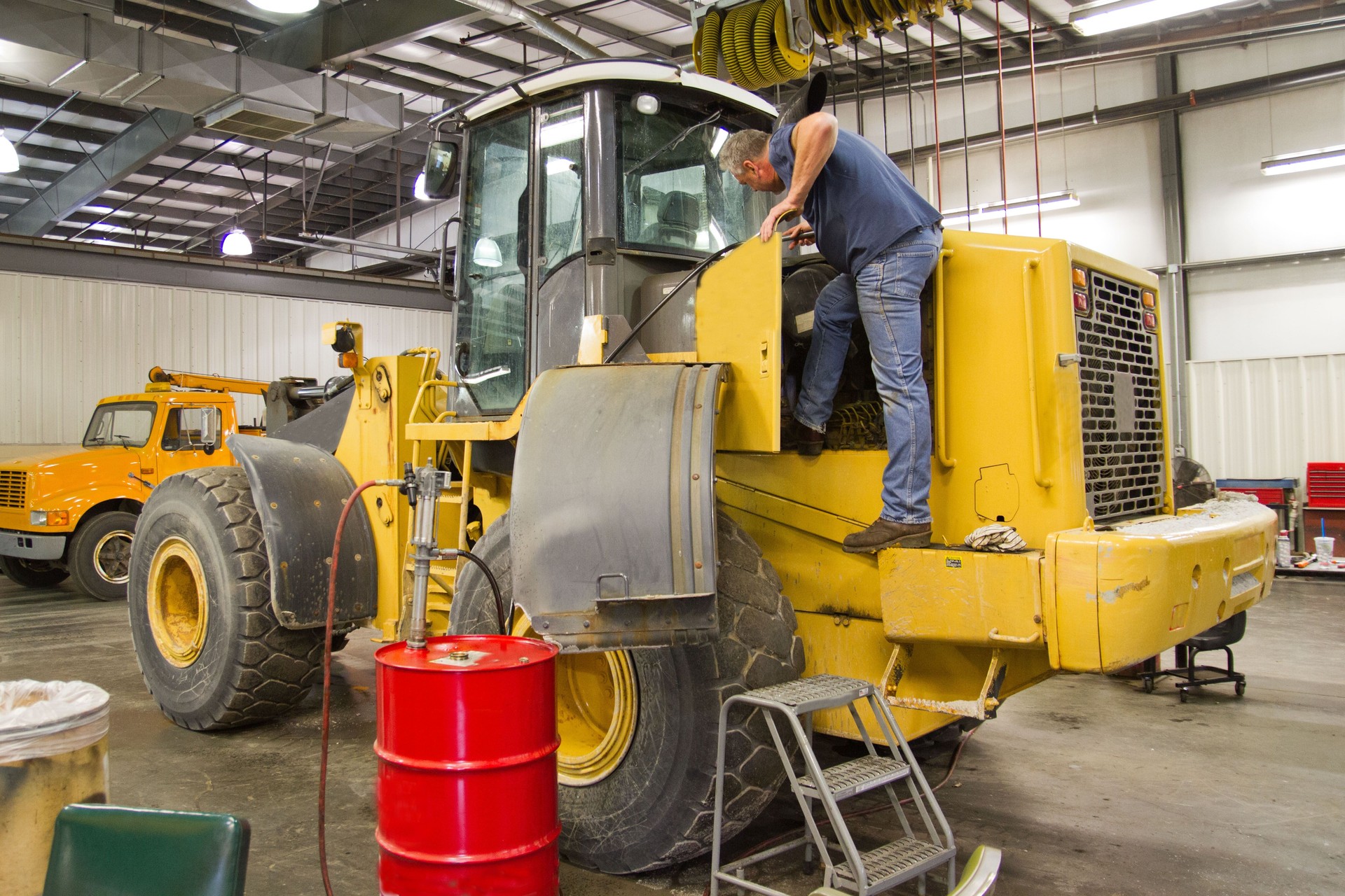Mechanic servicing front end loader, heavy equipment